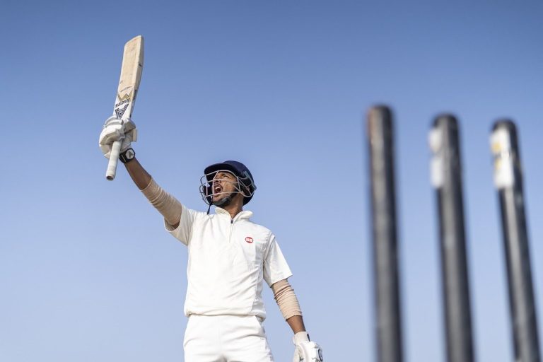 A cricketer waving his bat to show signs of victory