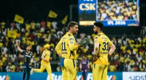MS Dhoni (jersey number 11) and Ruturaj Gaikwad (jersey number 31) in Chennai Super Kings' yellow kit engage in a mid-match tactical discussion on the field at a packed Chepauk Stadium, with the CSK scoreboard and a sea of yellow-clad fans visible in the background during IPL 2026.