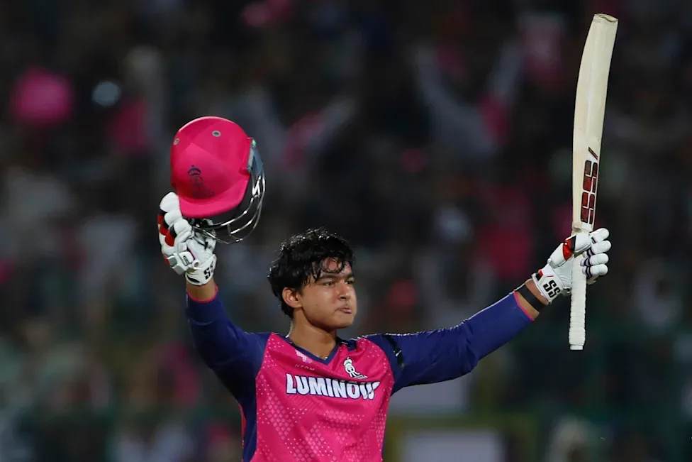 Vaibhav Sooryavanshi celebrates his record-breaking IPL century with his bat and helmet raised.