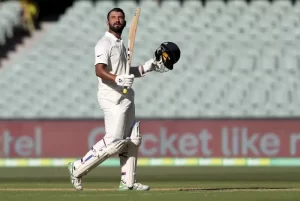 Indian Test batter in white cricket kit holding his bat and helmet after an innings, reflecting the patience and resilience highlighted in Cheteshwar Pujara’s biography.