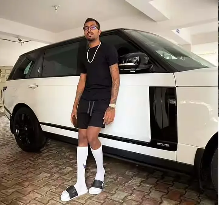 Hardik Pandya standing beside a white Range Rover from his reported luxury car collection.