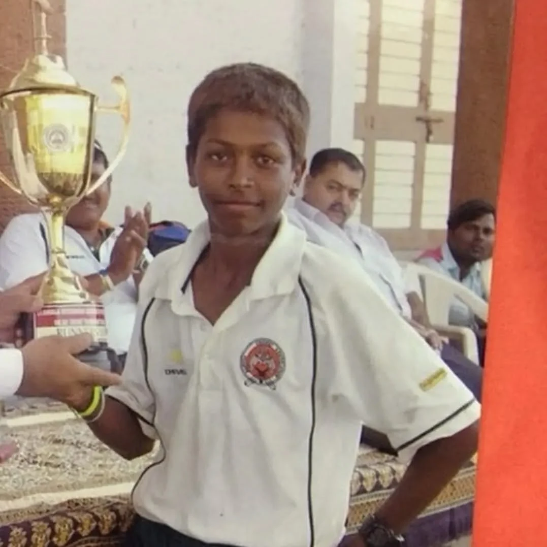 Young Hardik Pandya holding a cricket trophy during his early playing years in Gujarat.