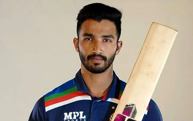 Devdutt Padikkal holding a cricket bat while wearing a blue cricket jersey in a professional portrait.