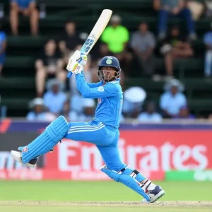 Young Indian top-order batter playing an attacking shot in India U-19 colours during a cricket match.
