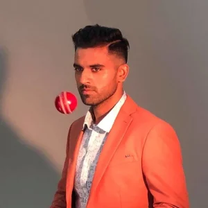 Indian fast bowler posing in an orange blazer with a red cricket ball