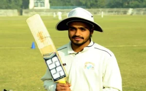 Young Prabhsimran Singh holding a cricket bat in white kit during his early cricket years in Punjab.
