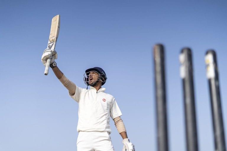 A cricketer waving his bat to show signs of victory