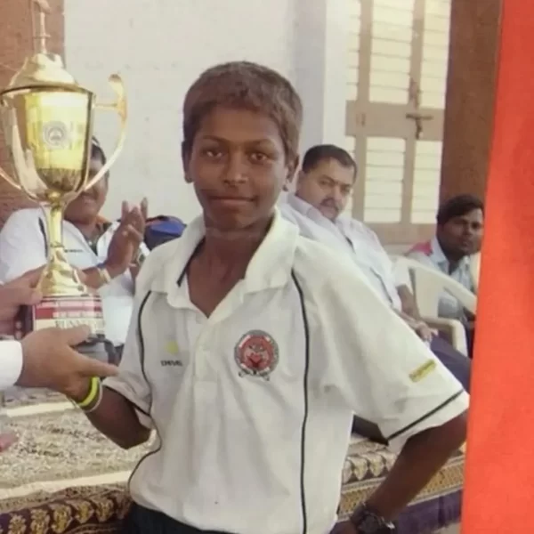 Young Hardik Pandya holding a cricket trophy during his early playing years in Gujarat.