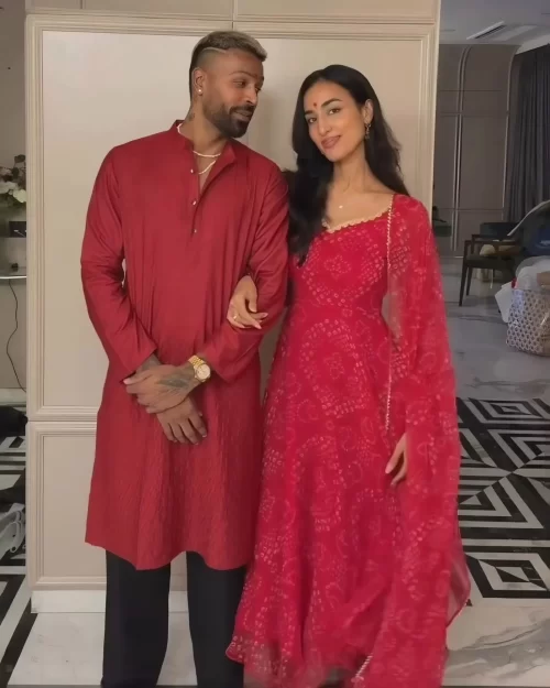 Hardik Pandya posing with girlfriend Mahieka Sharma while both wear coordinated red traditional outfits.