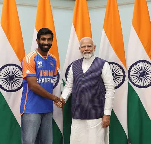 Indian fast bowler in a blue championship jersey shaking hands with a national leader in front of multiple Indian flags
