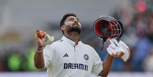 Rishabh Pant celebrating in India’s Test jersey while holding his helmet and batting gloves.
