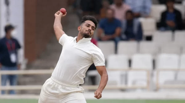 Umran Malik delivering a red ball in white cricket clothing during a domestic match.